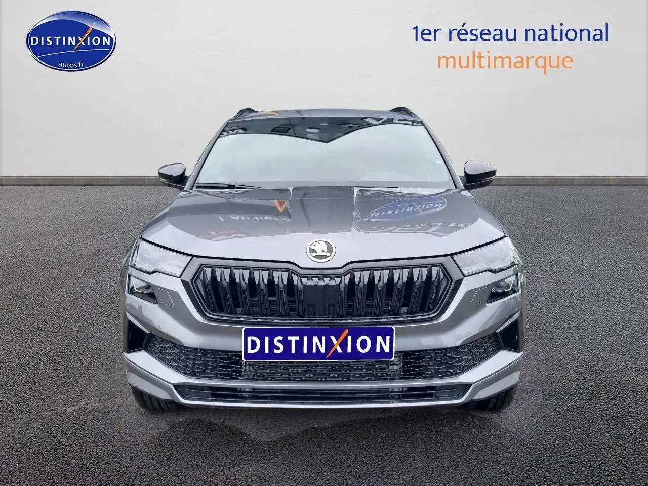 Vue frontale d'un SUV SKODA KAROQ gris graphite avec calandre noire et logo centré sur fond neutre.