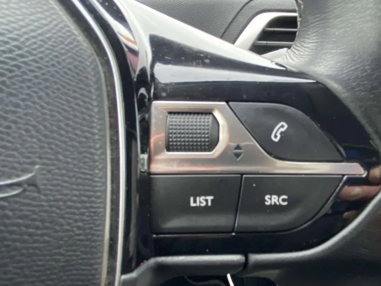 Gros plan sur les commandes multifonctions du volant noir du Peugeot 3008 marron foncé de 2017.