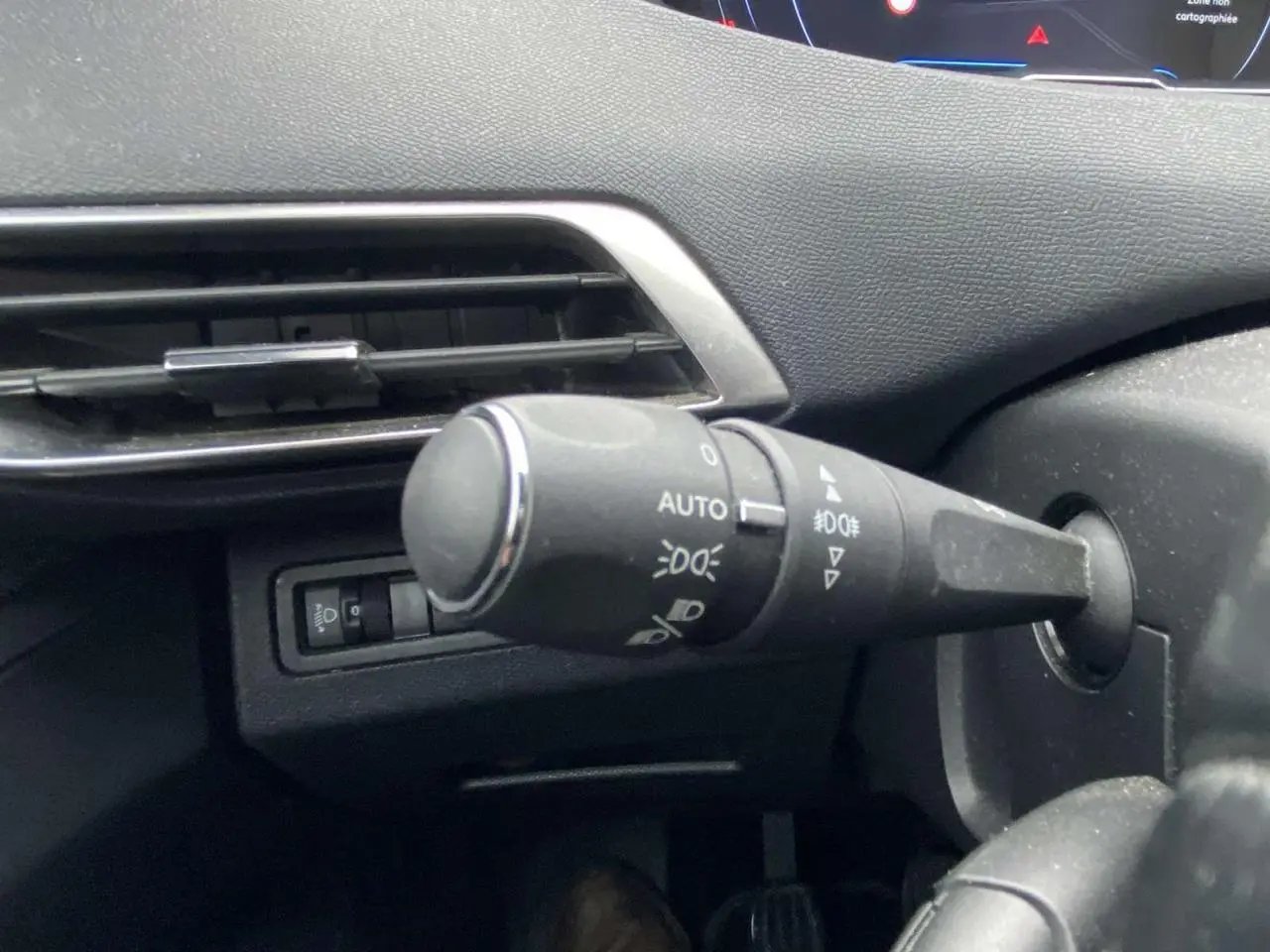 Gros plan sur la commande des feux du tableau de bord du Peugeot 3008 marron foncé, version 2017 Allure.