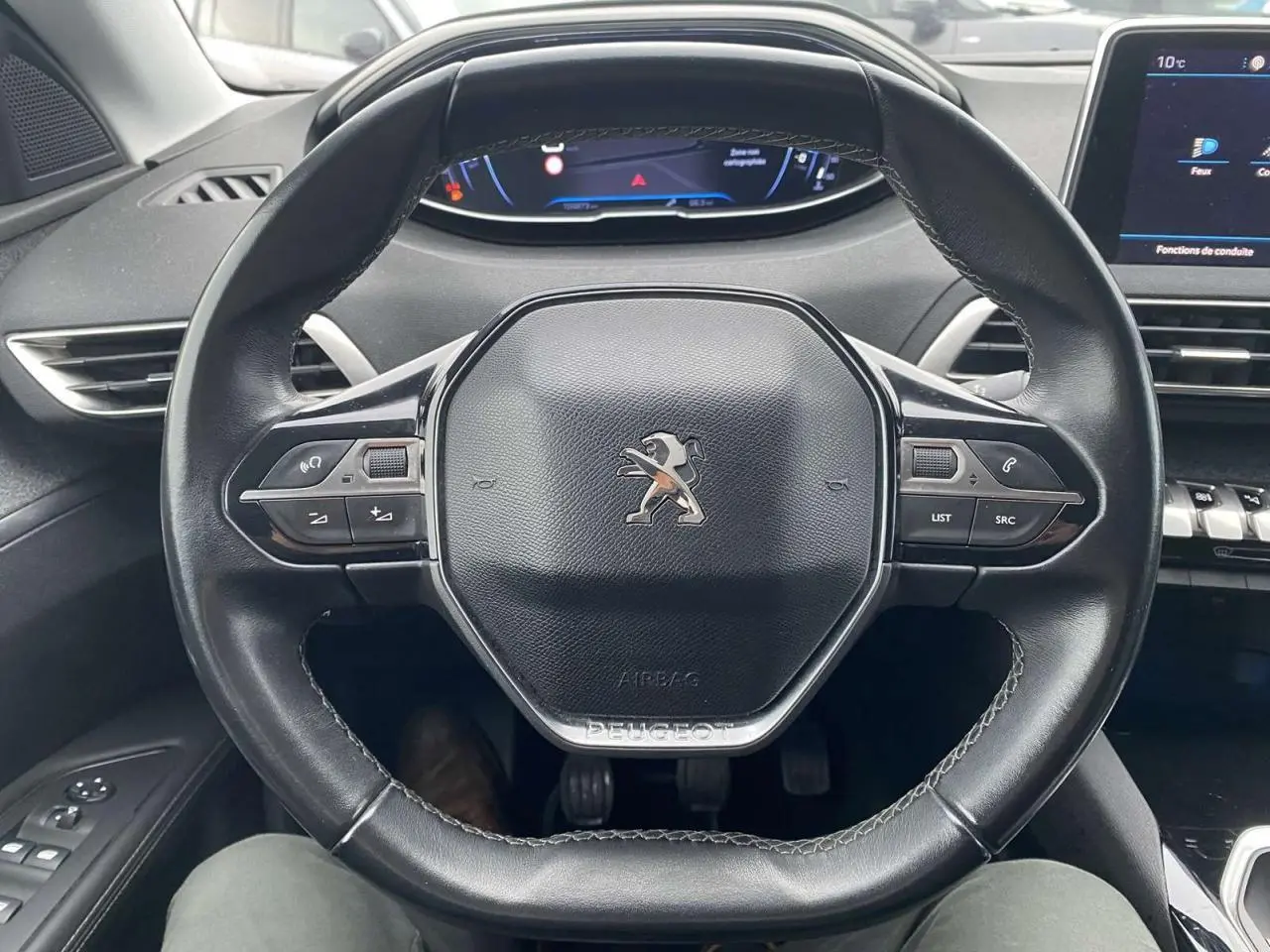 Vue rapprochée du volant compact en cuir noir du Peugeot 3008 avec commandes intégrées et tableau de bord numérique.