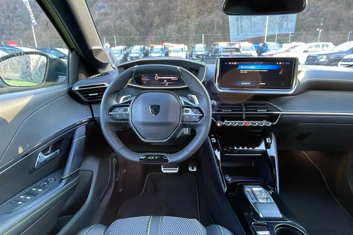 Intérieur du Peugeot 208 Hybrid 136 GT Plus 2024, vue frontale du poste de conduite avec volant compact et écran tactile.