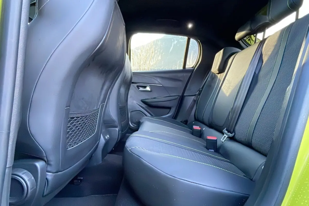 Vue intérieure arrière droite des sièges noirs avec surpiqûres vertes du Peugeot 208 Hybrid 136 GT Plus 2024.