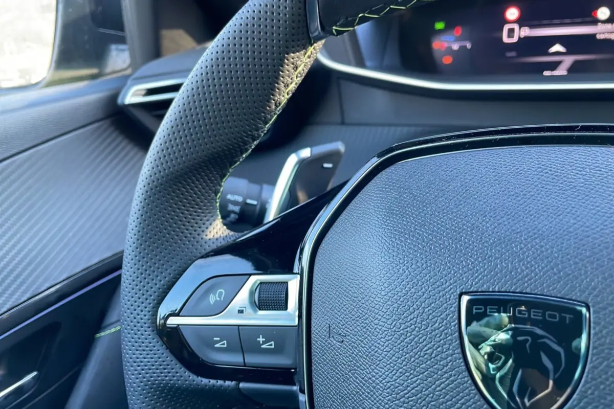 Gros plan sur le volant perforé et les commandes du côté gauche du Peugeot 208 Hybrid 136 GT Plus 2024.