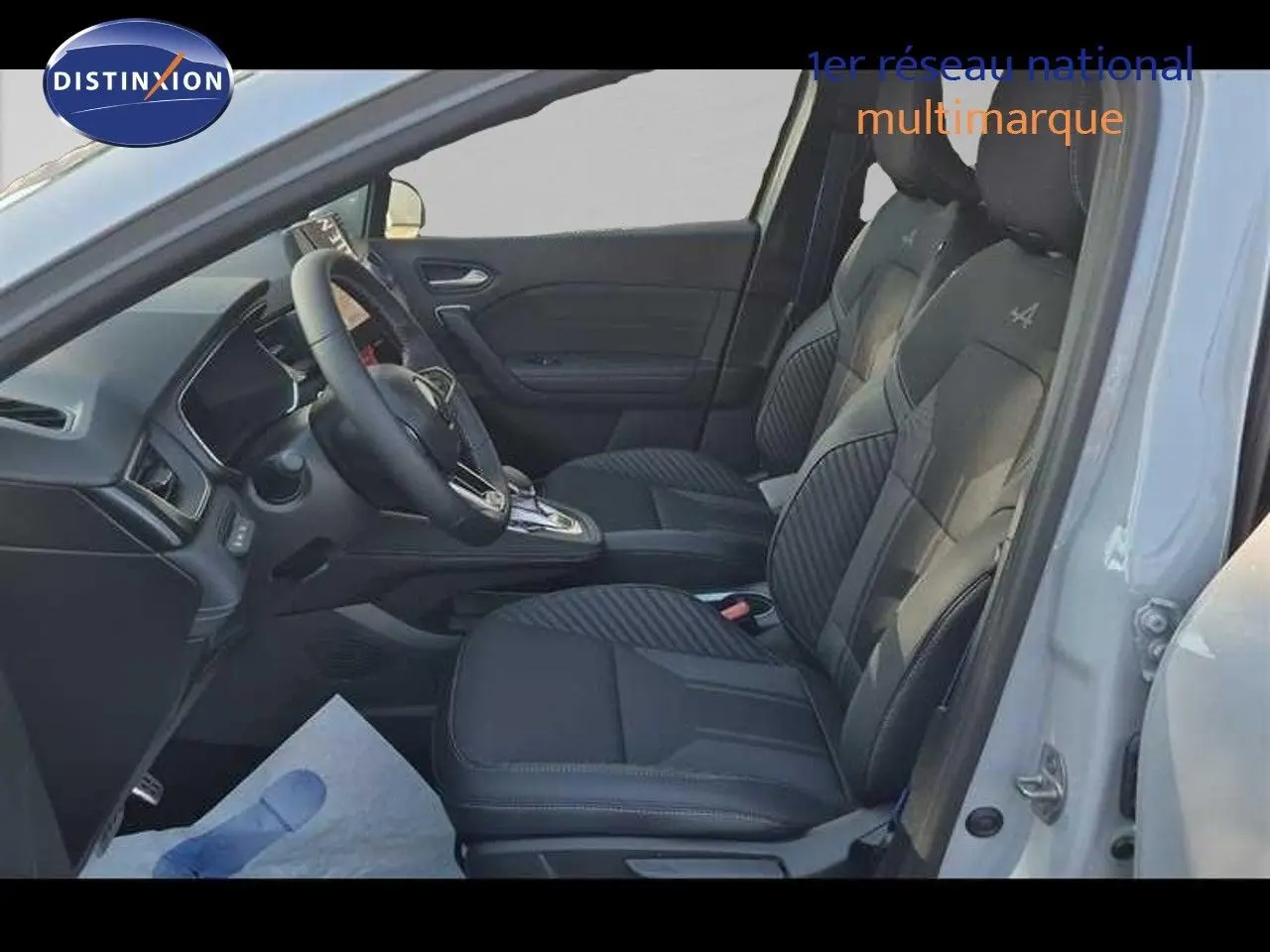 Vue intérieure côté conducteur du Renault Captur gris Rafale, sièges noirs avec surpiqûres et volant multifonction.