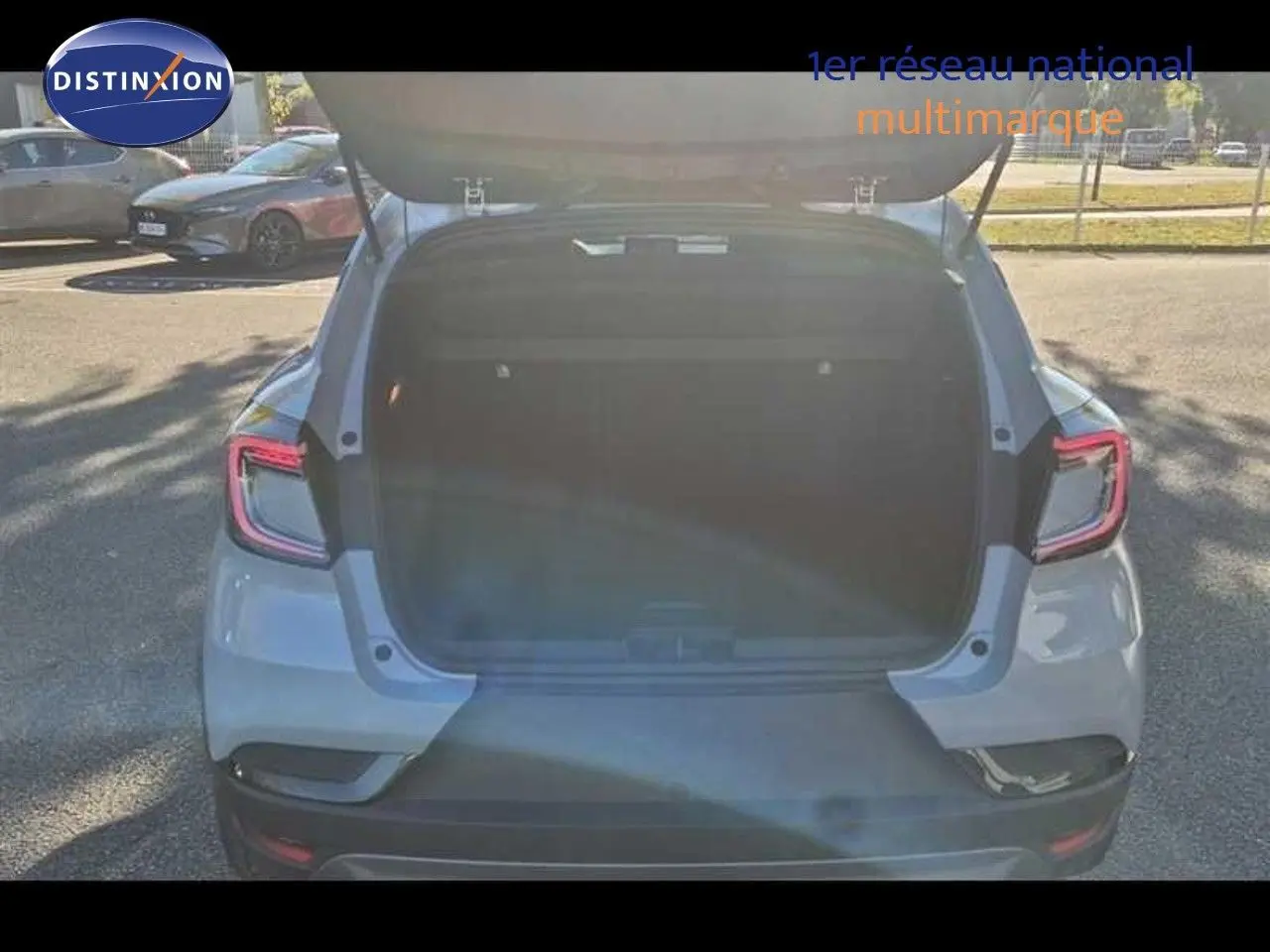 Vue arrière du Renault Captur E-Tech hybride gris Rafale avec coffre ouvert, mettant en valeur ses feux LED distinctifs.