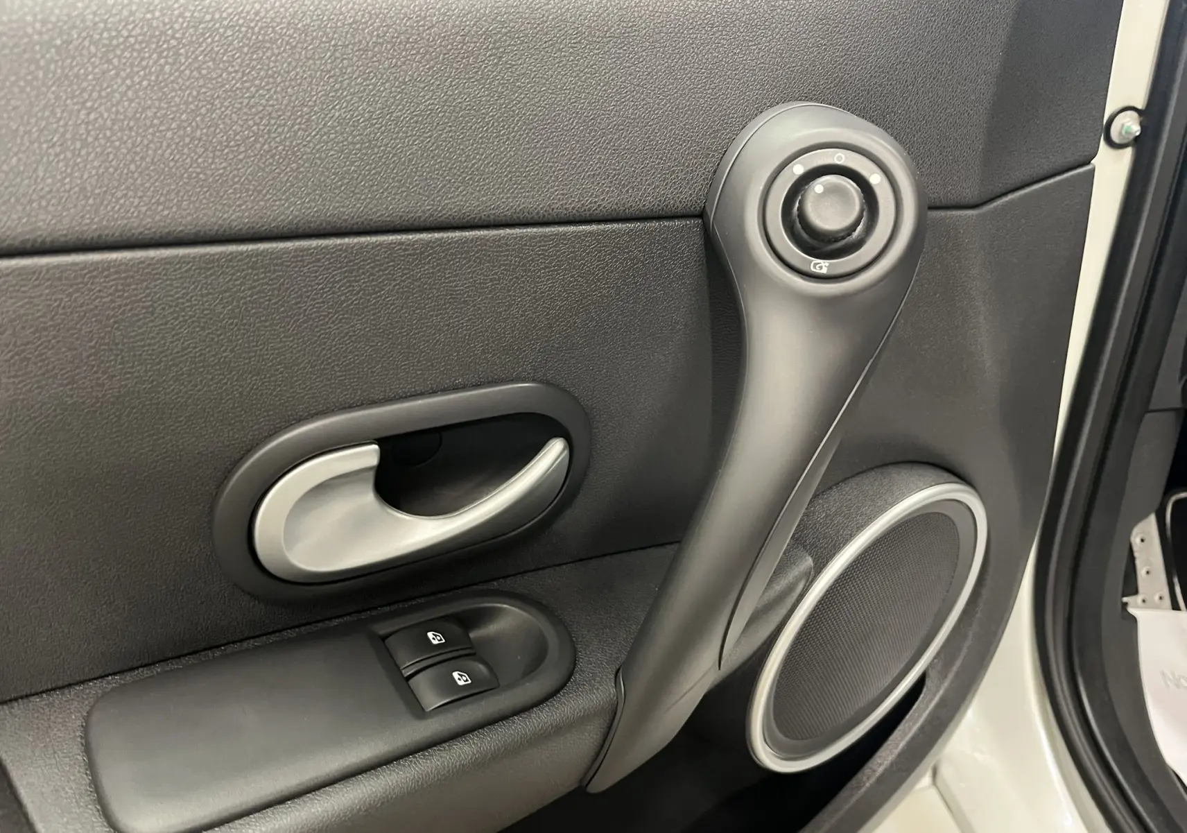 Détail de la porte côté gauche d'une Renault Clio III RS 20TH Anniversary blanc nacré, avec poignée argent et commandes électriques.