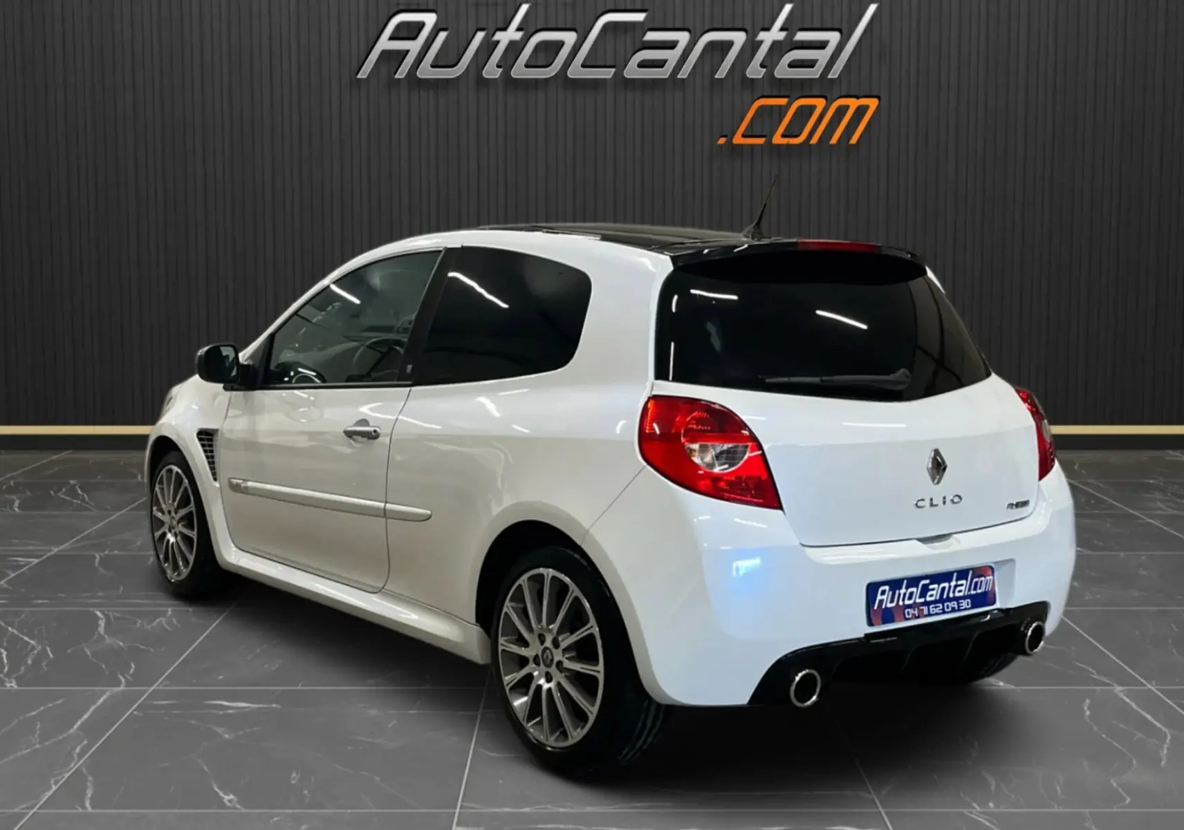 Vue 3/4 arrière droite d'une Renault Clio III RS 20th Anniversary blanc nacré avec toit noir et jantes alliage 17 pouces.