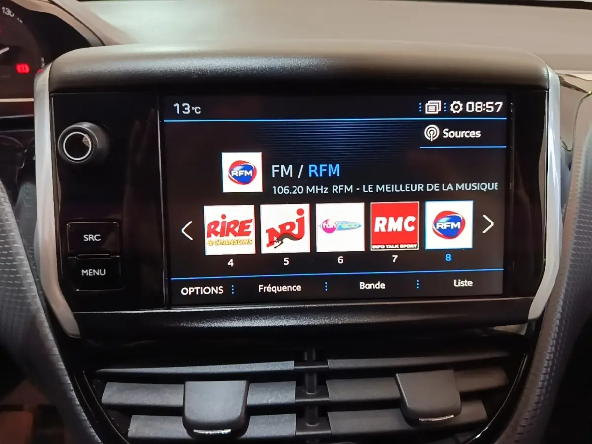 Vue rapprochée de l’écran tactile central du Peugeot 2008 noir affichant les stations radio avec commandes autour.