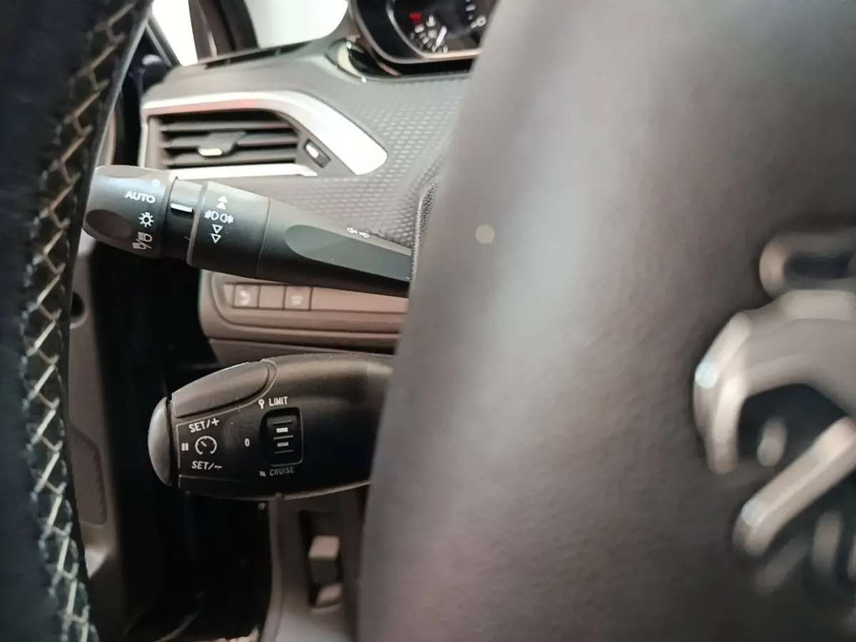 Gros plan sur le volant cuir noir et les commandes de régulateur de vitesse de la Peugeot 2008 Puretech 2019.
