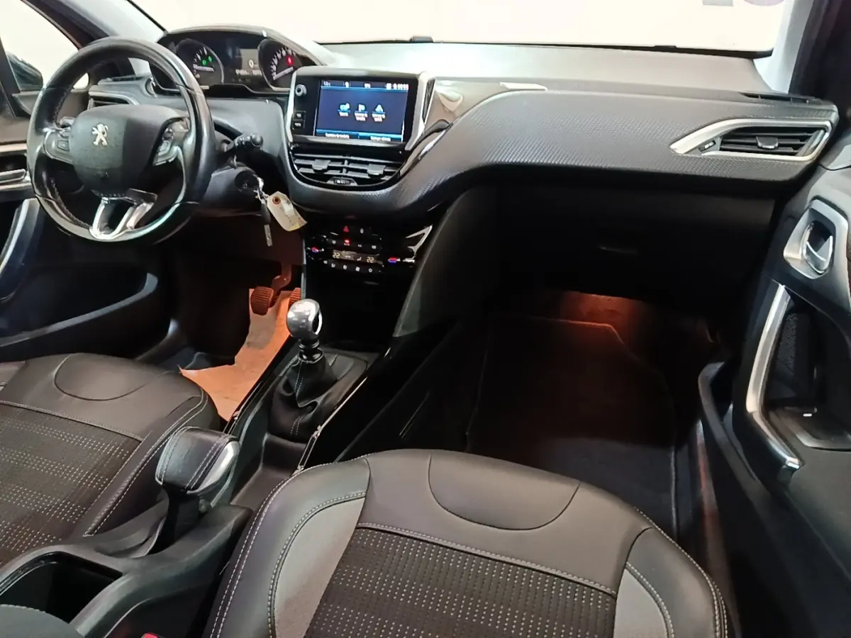 Vue intérieure avant droite du Peugeot 2008 noir, montrant le tableau de bord avec écran tactile et volant cuir multifonctions.