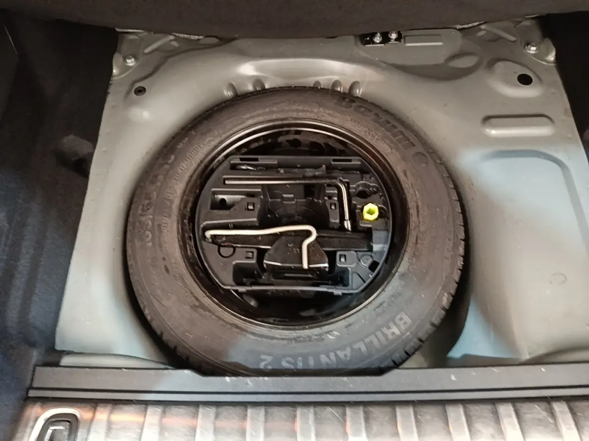 Vue plongeante sur la roue de secours en jante acier noire dans le coffre du Peugeot 2008 noir 2019.
