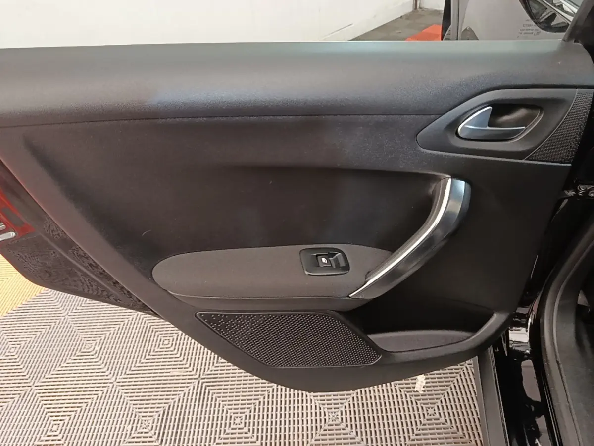 Vue intérieure sur la porte avant gauche noire d’une Peugeot 2008 avec poignée argentée et commande de vitre.
