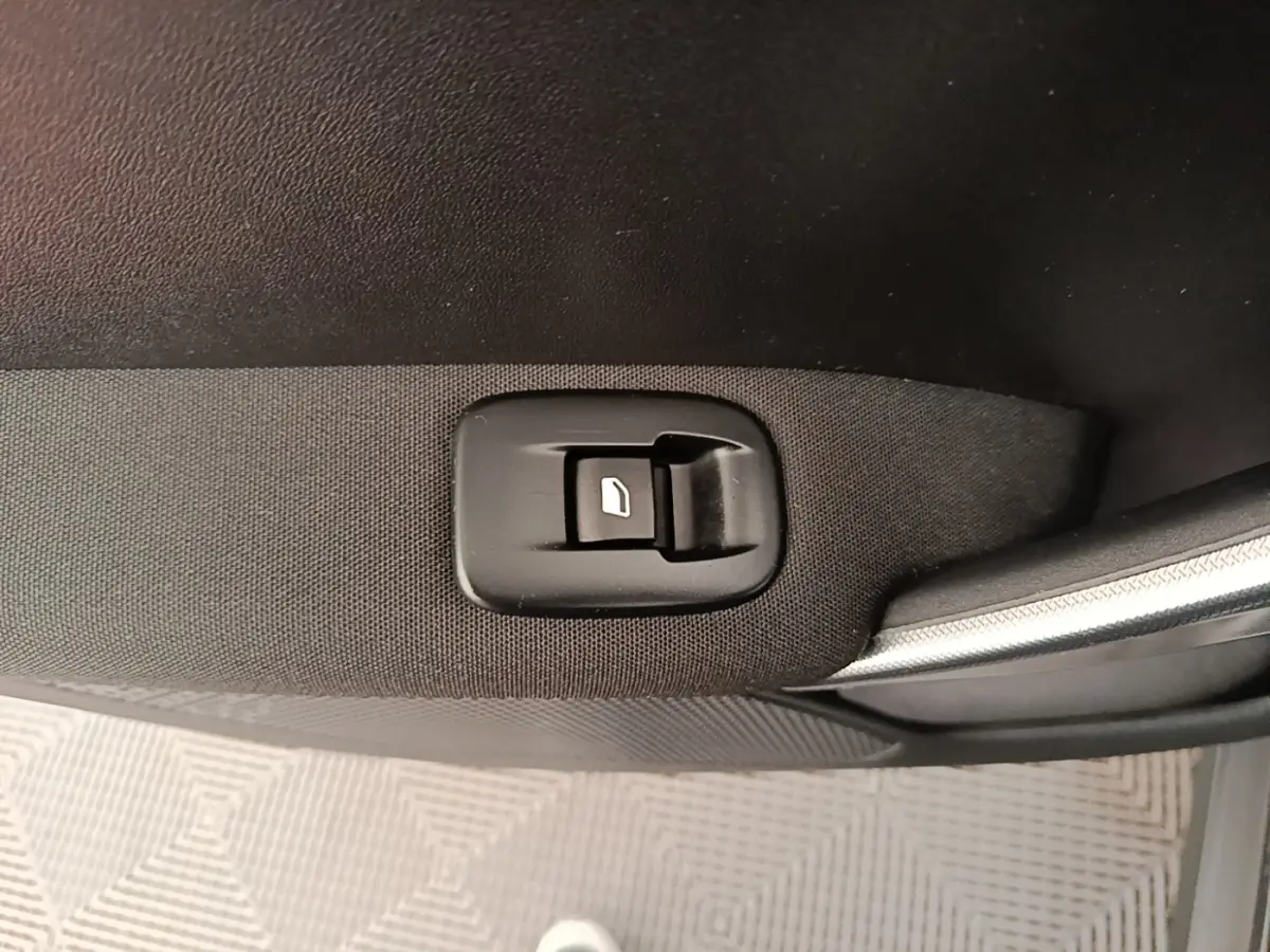 Gros plan sur le bouton de commande de la vitre électrique côté porte avant droite d’une Peugeot 2008 noire.