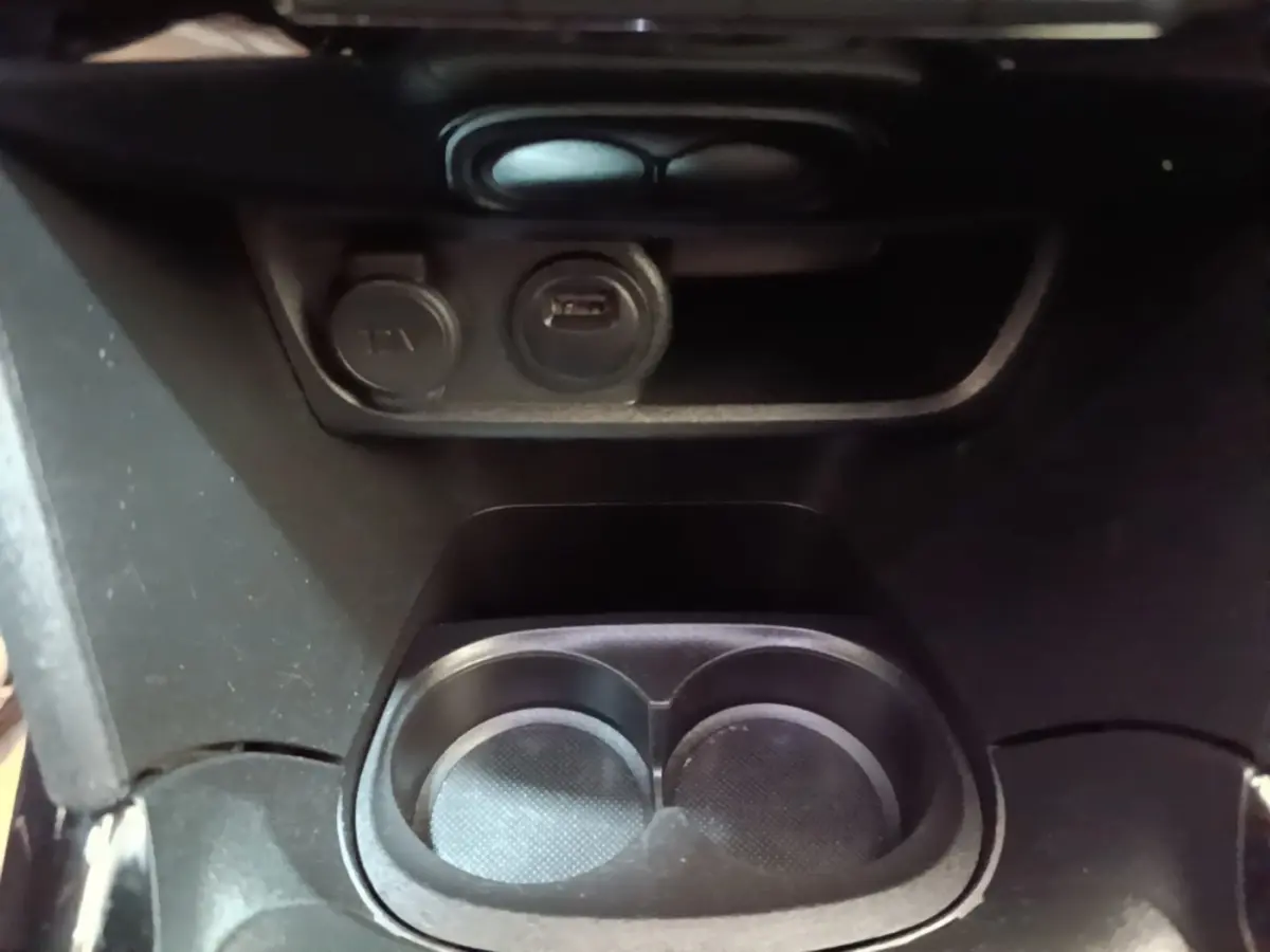 Gros plan sur la console centrale noire du Peugeot 2008 avec porte-gobelets et prises 12V et USB visibles.