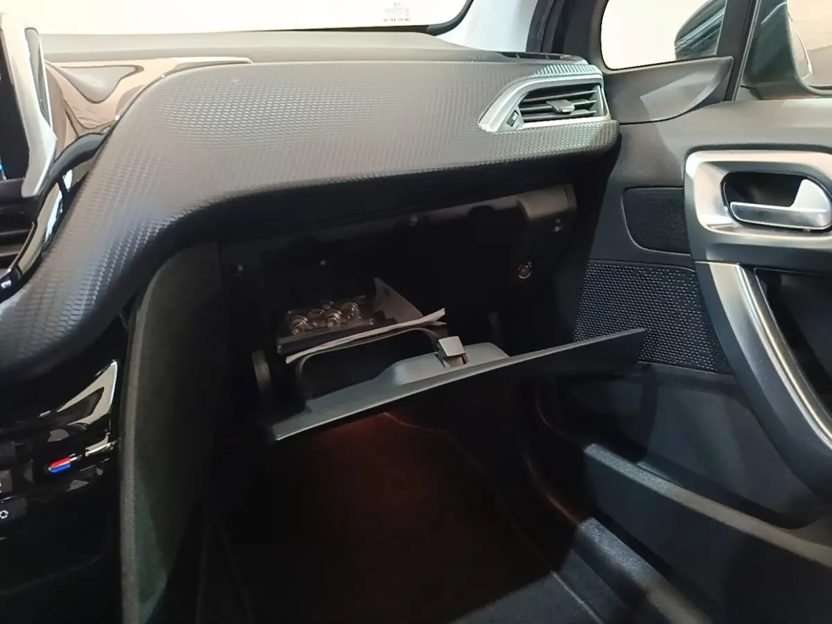Intérieur côté passager du Peugeot 2008 noir, avec boîte à gants ouverte et tableau de bord texturé noir.