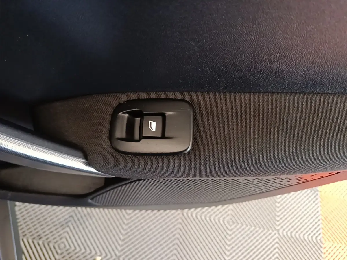 Détail du bouton de commande de la vitre sur la porte intérieure côté droit d’un Peugeot 2008 noir.