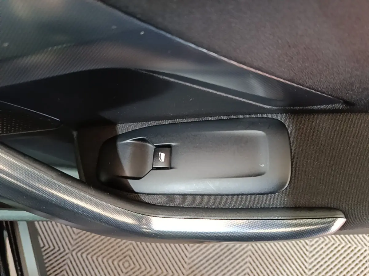 Gros plan sur la commande d'ouverture de coffre intérieur noir dans une Peugeot 2008 Puretech 130 S&S Allure Business 2019.