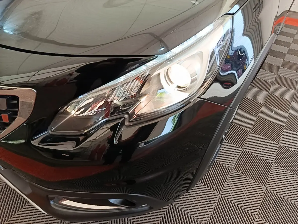 Gros plan sur le phare avant droit d’un Peugeot 2008 noir brillant, avec calandre et pare-chocs visibles.