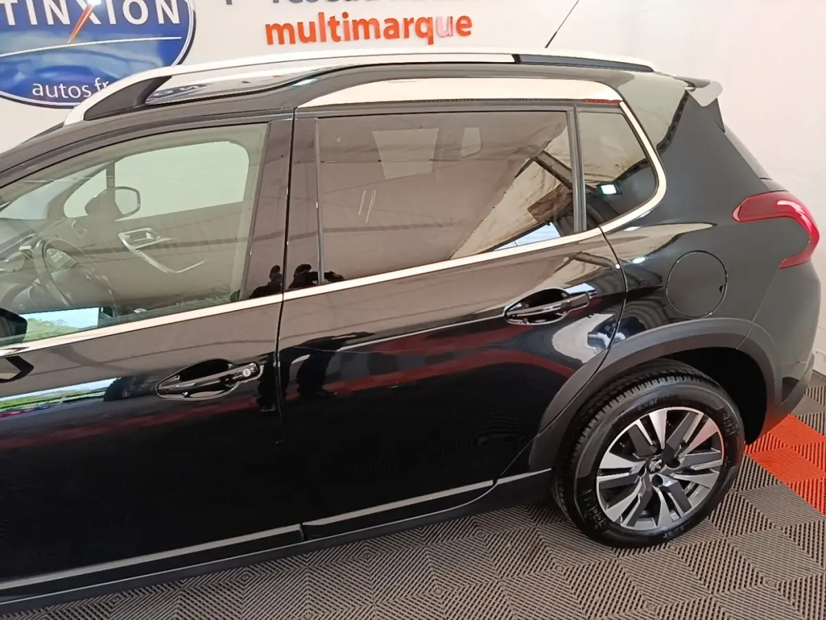 Profil droit d’un Peugeot 2008 noir 2019 avec jantes alliage et rails de toit chromés visibles.