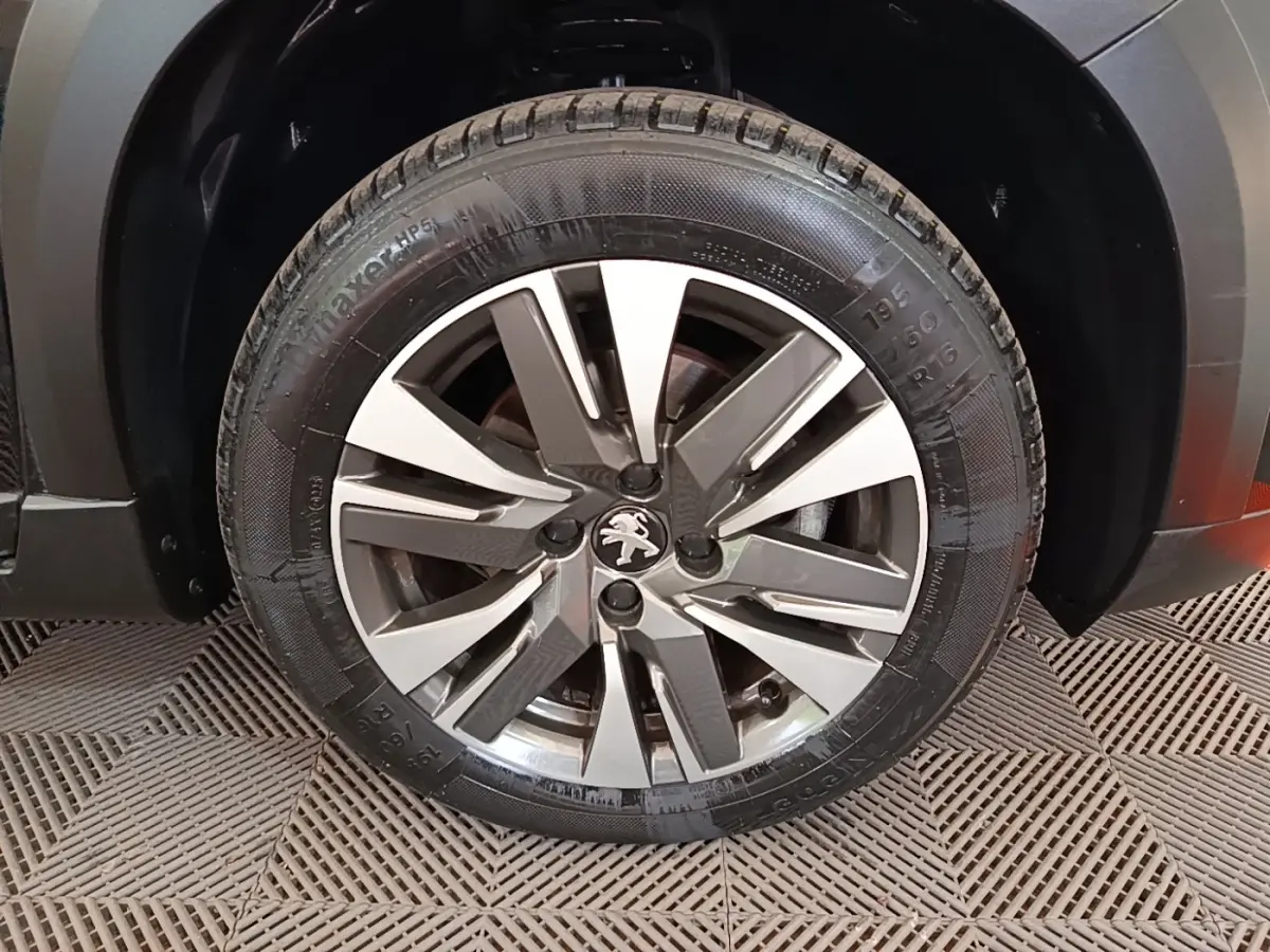 Gros plan sur la roue avant droite d'un Peugeot 2008 noir, mettant en valeur la jante alliage au design moderne.