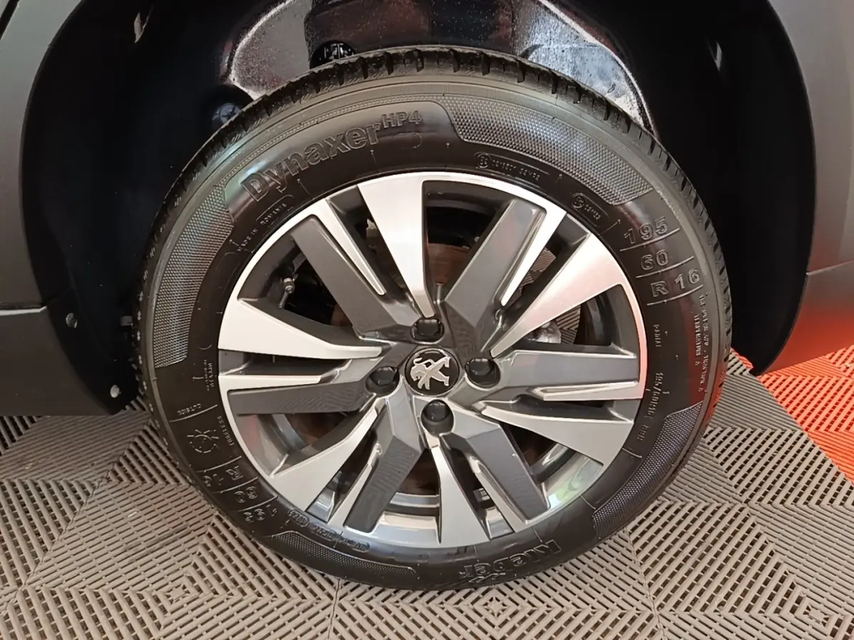 Gros plan sur la roue avant droite d’un Peugeot 2008 noir, avec jante alliage et logo lion au centre.