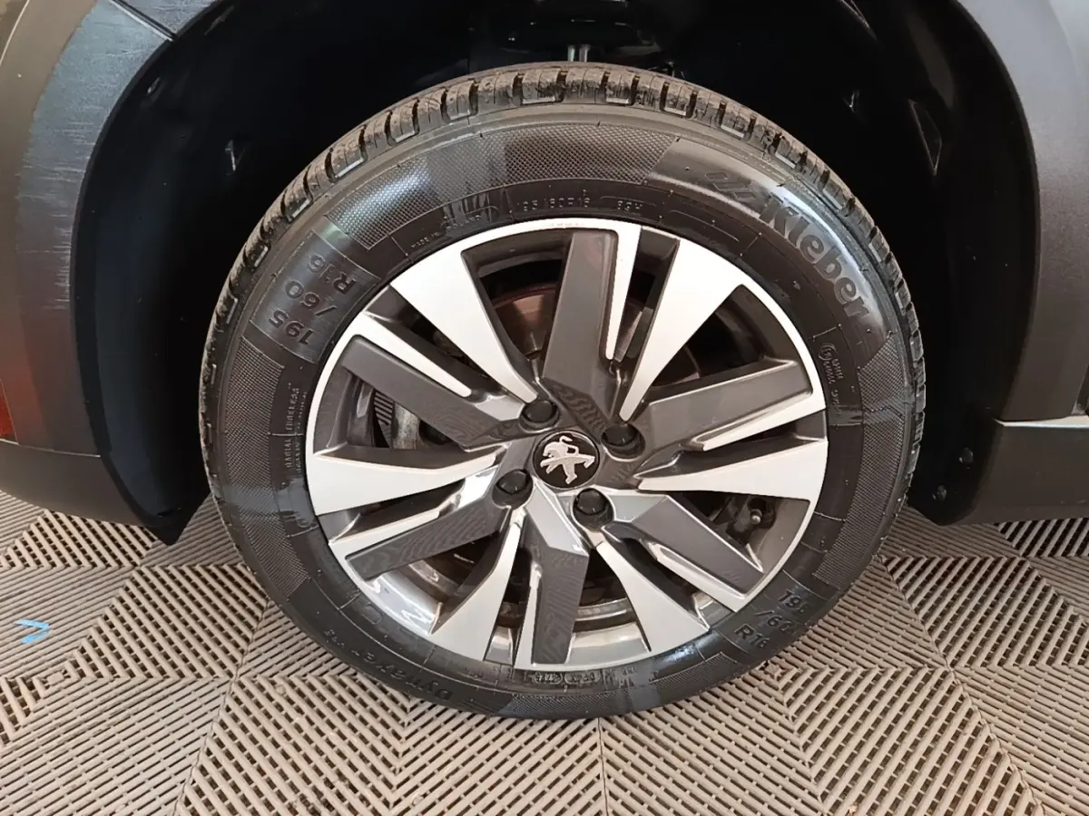 Gros plan sur la roue avant droite du Peugeot 2008 noir, mettant en valeur la jante alliage au design moderne.