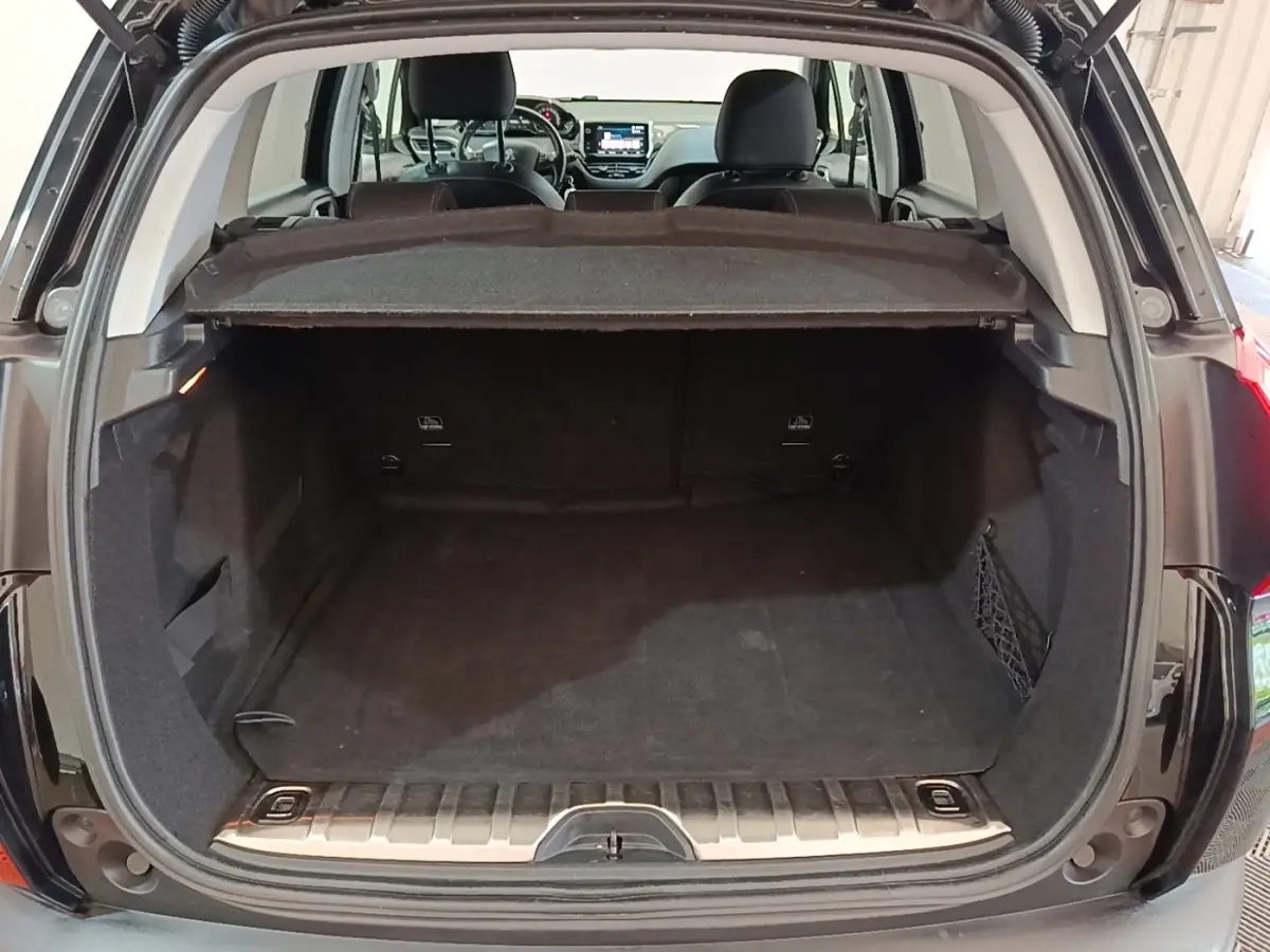 Coffre ouvert d’un Peugeot 2008 noir vu de l’arrière, montrant l’espace de chargement et la tablette cache-bagages.