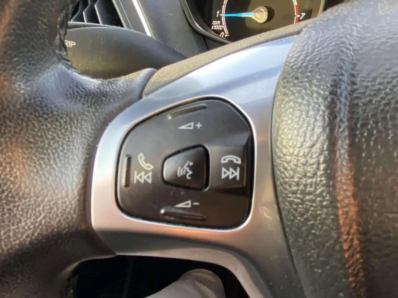 Gros plan sur les commandes vocales et audio au volant du Ford B-MAX blanc 2014, version Titanium.