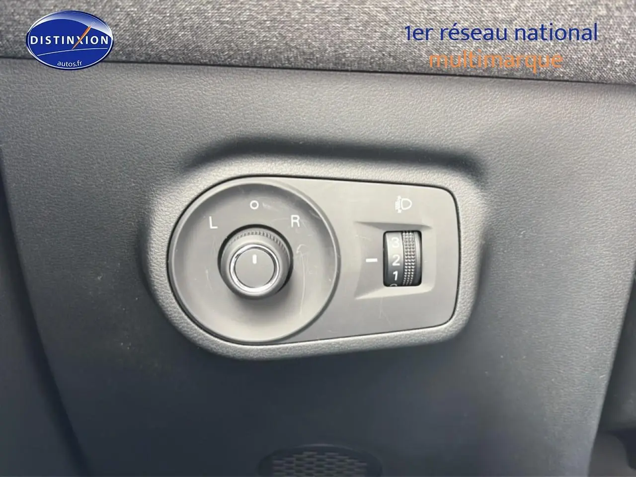 Gros plan sur les commandes de réglage des rétroviseurs et des phares du MG ZS Hybrid blanc, côté conducteur.