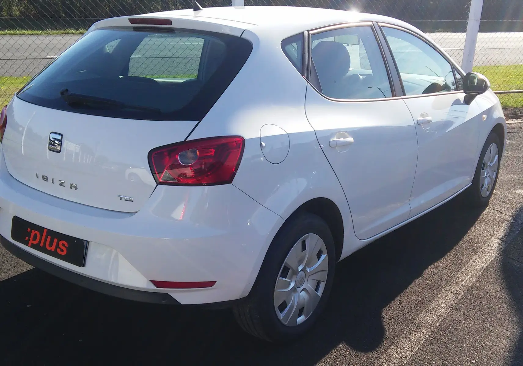 SEAT Ibiza Business blanche vue en 3/4 arrière droit, avec feux arrière rouges et jantes acier simples.
