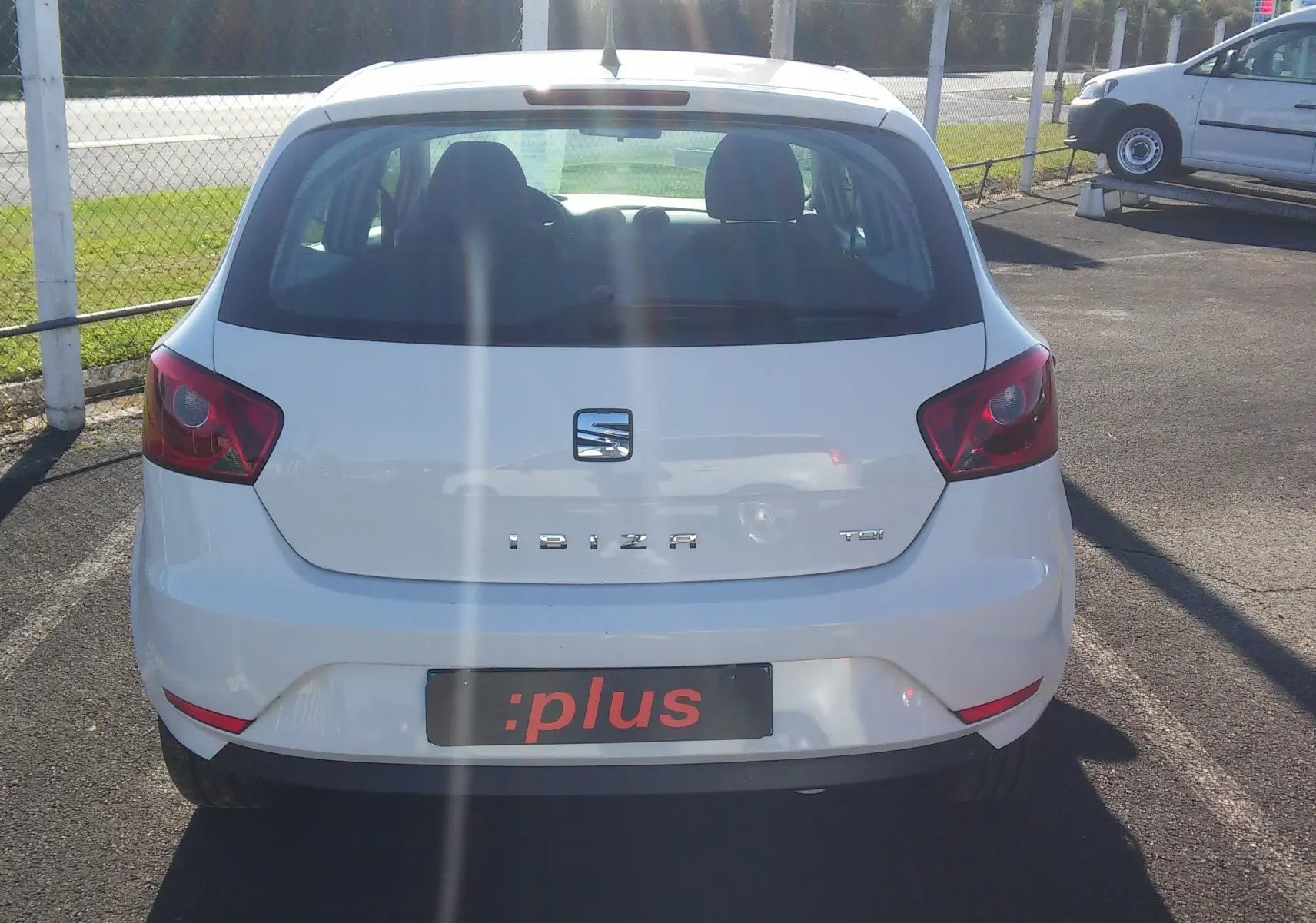 Vue arrière d'une SEAT Ibiza Business blanche de 2015, avec logo et feux arrière visibles sur un parking.