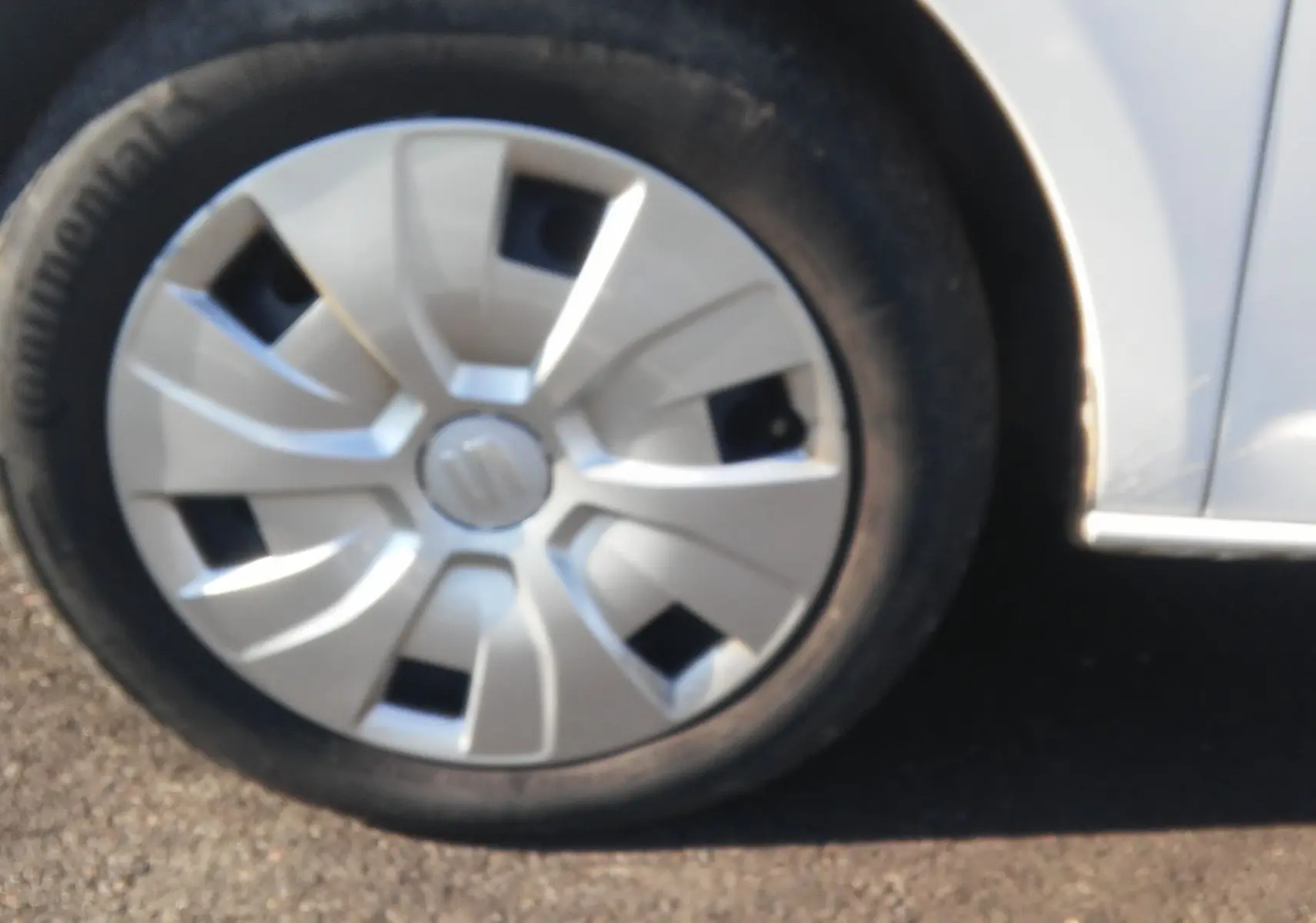 Gros plan sur la roue avant gauche blanche d'une SEAT Ibiza Business 2015 avec enjoliveur d'origine.