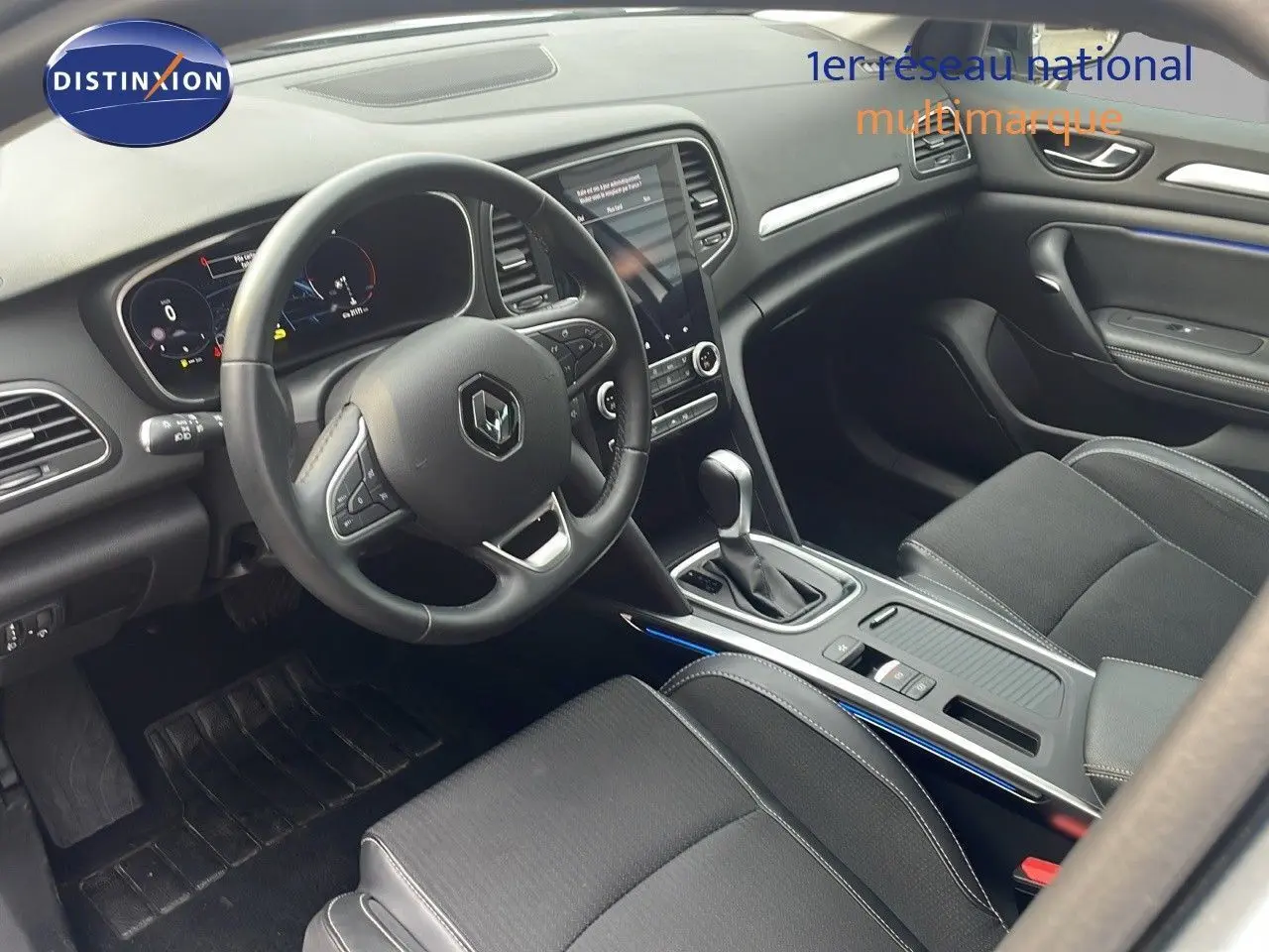 Intérieur avant de la Renault Mégane Break 2024, volant multifonction et console centrale avec boîte automatique.