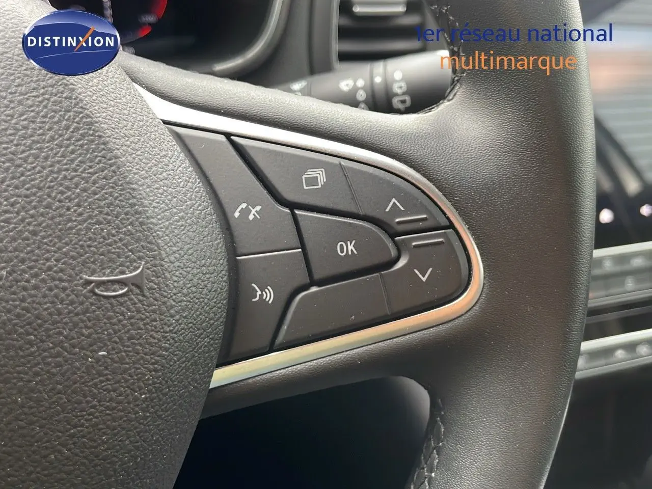 Gros plan sur les commandes au volant en cuir noir de la Renault Mégane Break 2024, version diesel gris Highland Metal.