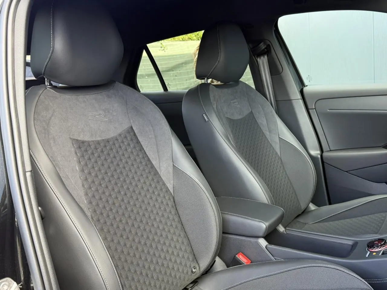 Vue intérieure des sièges avant en tissu gris et cuir noir du Volkswagen T-Roc 2026 version R-Line.
