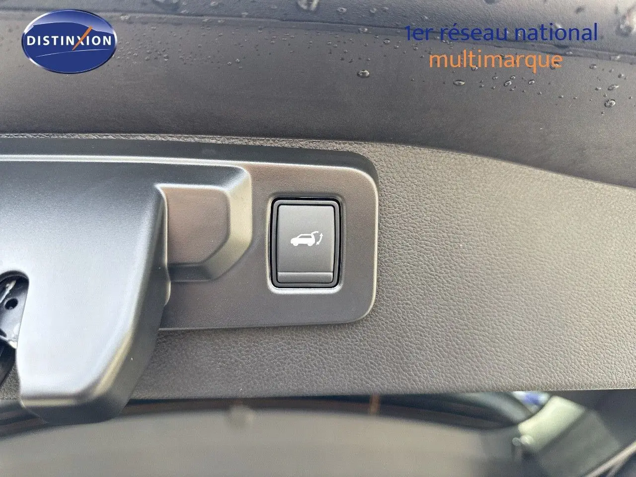 Bouton d'ouverture électrique du coffre sur le hayon intérieur d'un Renault Austral gris schiste métal toit noir.