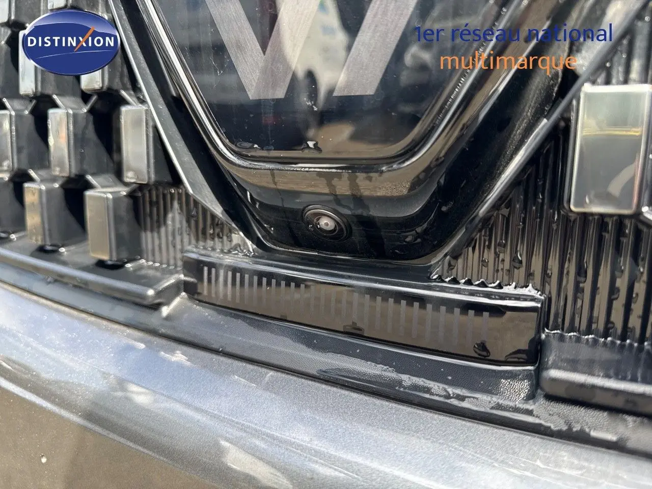 Gros plan sur la calandre et caméra avant du Renault Austral gris schiste métal avec toit noir, version hybride 2024.