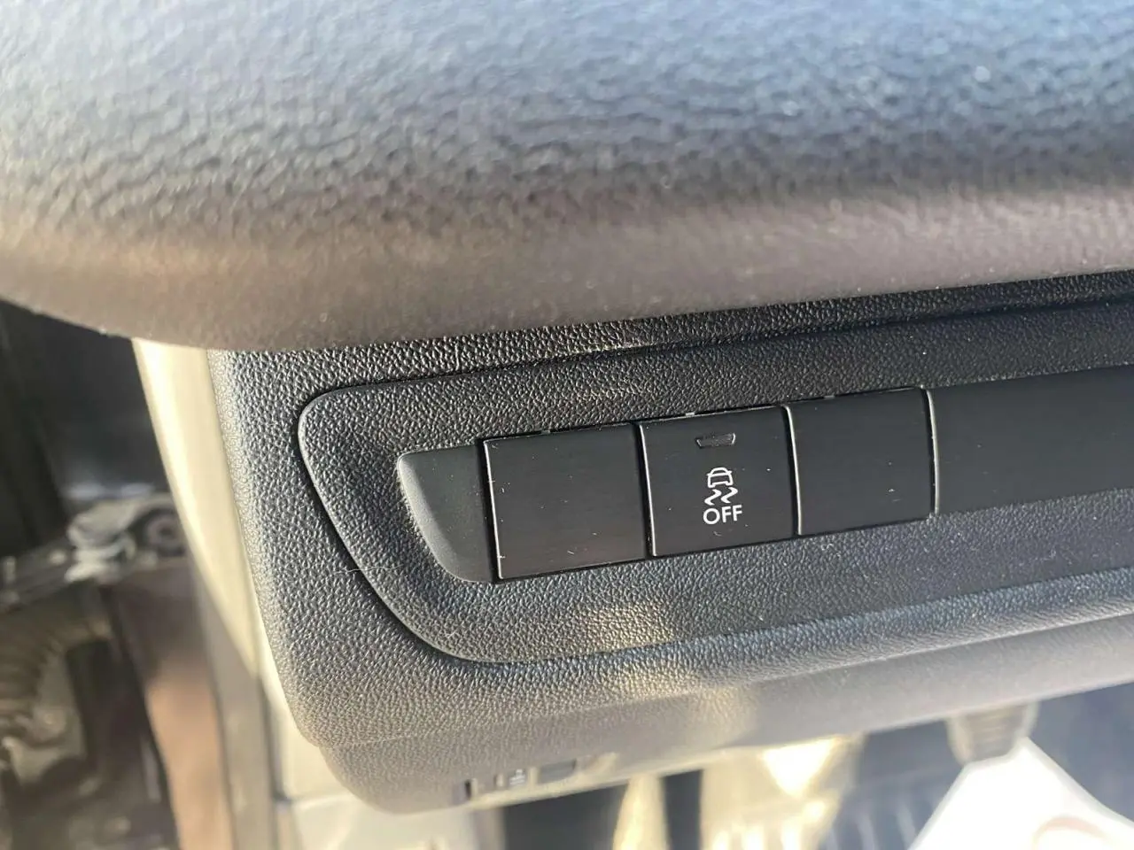 Gros plan sur le bouton de désactivation de l'ESP dans l'habitacle d'une Peugeot 208 noire de 2016.