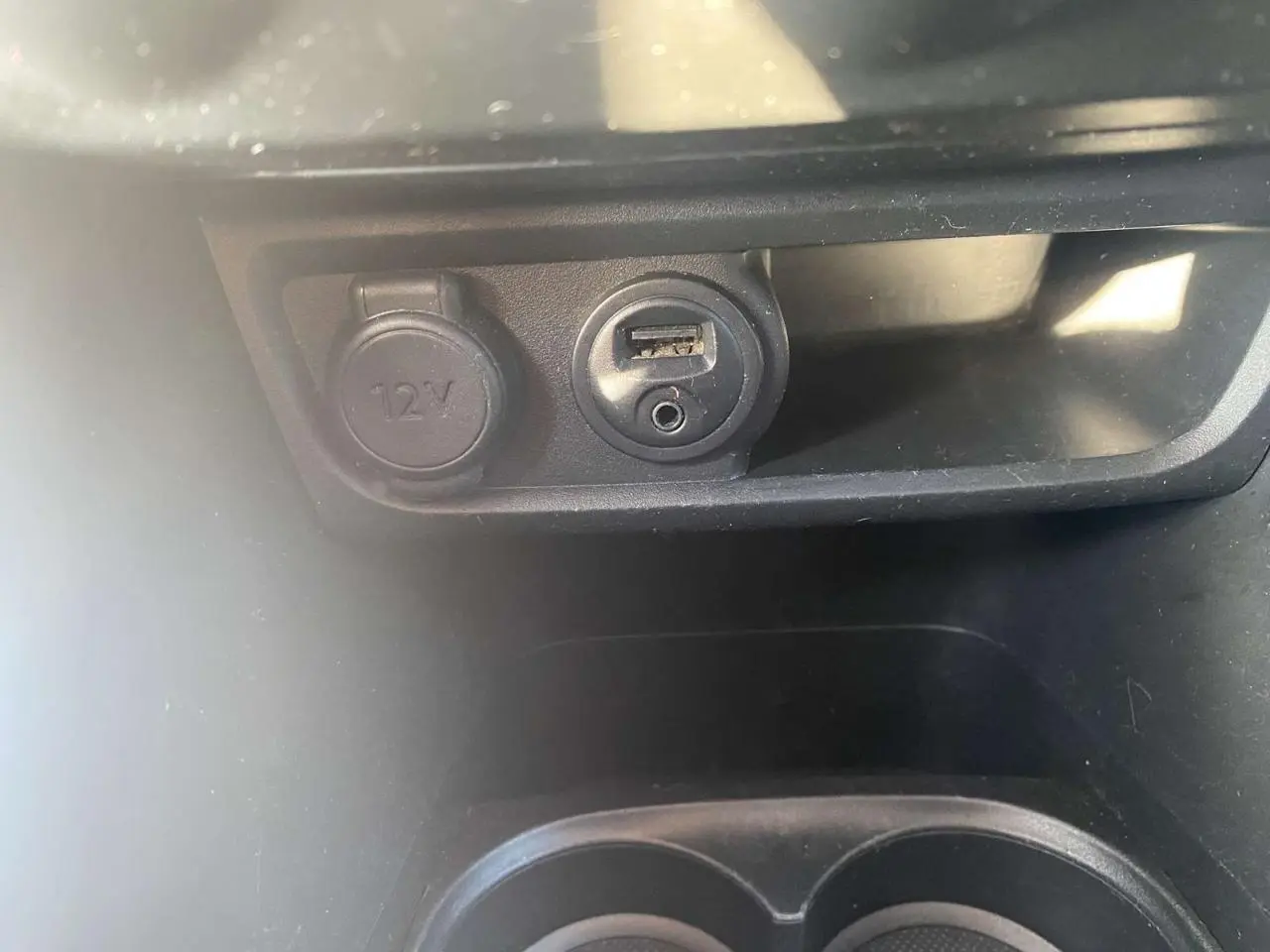 Prise 12V et port USB en gros plan dans l'habitacle d'une Peugeot 208 noire 2016 version Active+ GPS.