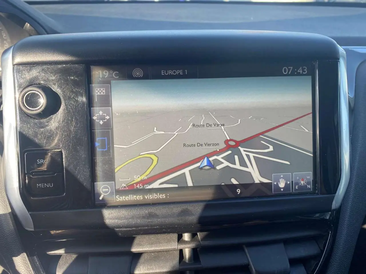 Écran tactile GPS de la Peugeot 208 noire 2016, vue rapprochée du tableau de bord avec navigation affichée.