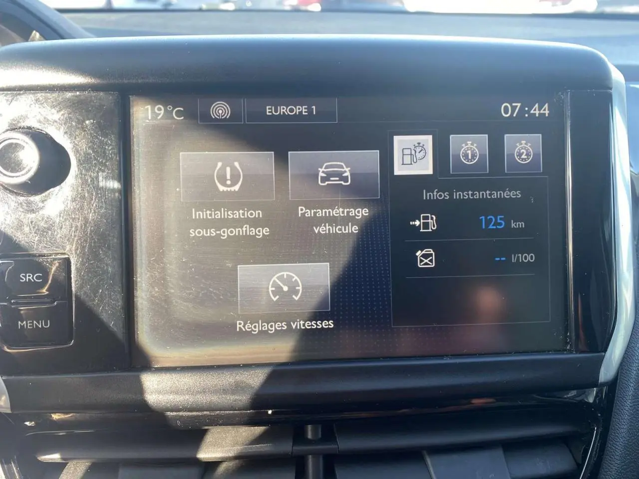 Écran tactile central de la Peugeot 208 noire affichant les réglages de vitesse et l'autonomie à 125 km.