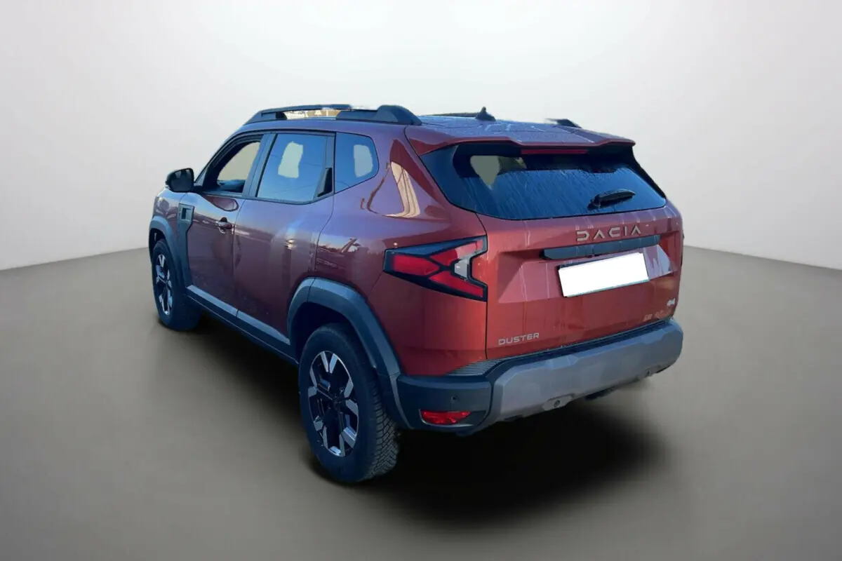 Vue 3/4 arrière droite du Dacia Duster 2024 brun terracotta avec jantes noires et détails noirs contrastants.
