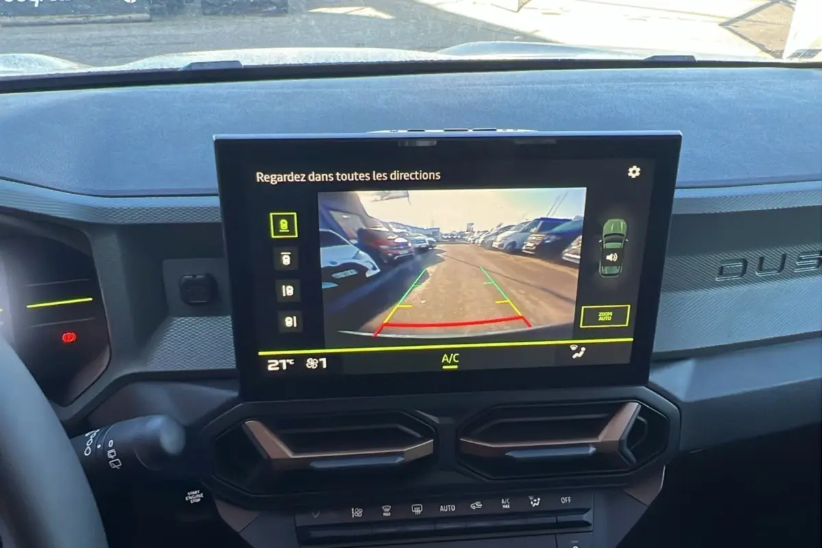 Écran central du tableau de bord du Dacia Duster 2024 montrant la caméra de recul avec vue arrière sur un parking.
