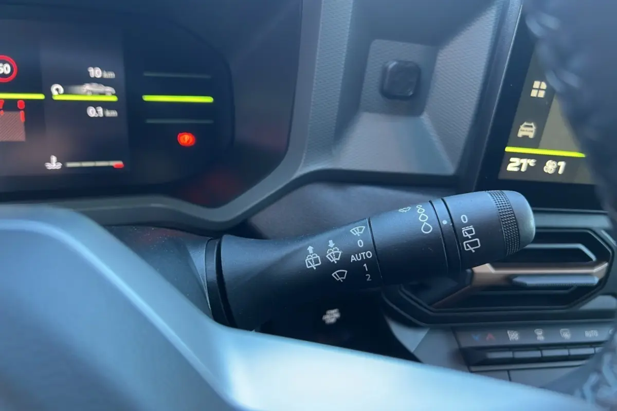 Le commodo des essuie-glaces dans l'habitacle du Dacia Duster 2024 brun terracotta, avec tableau de bord numérique.