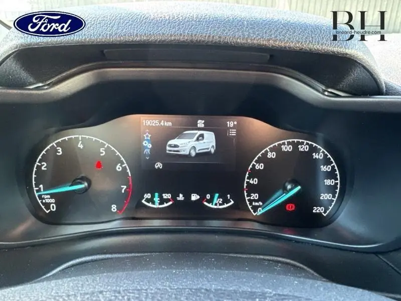 Vue rapprochée du tableau de bord numérique du Ford Transit Connect blanc glacier avec affichage du véhicule et compteurs analogiques.