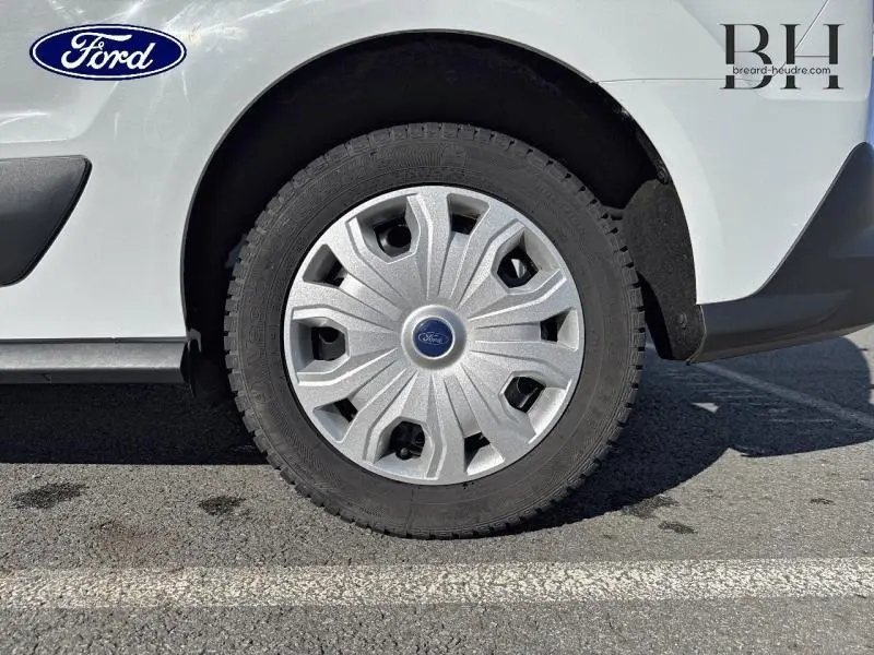 Gros plan sur la roue avant droite d'un Ford Transit Connect blanc glacier avec enjoliveur argenté et logo Ford central.