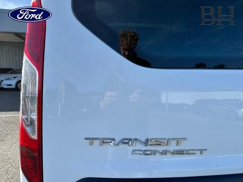 Gros plan sur l'arrière blanc glacier du Ford Transit Connect avec logo et feu arrière gauche visible.