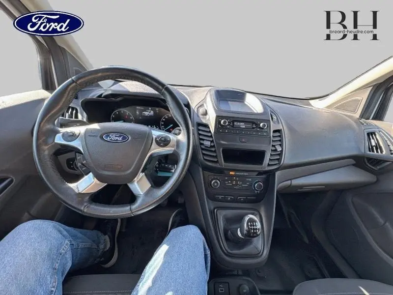 Vue intérieure du tableau de bord et volant multifonction du Ford Transit Connect blanc glacier, avec levier de vitesses manuel visible.