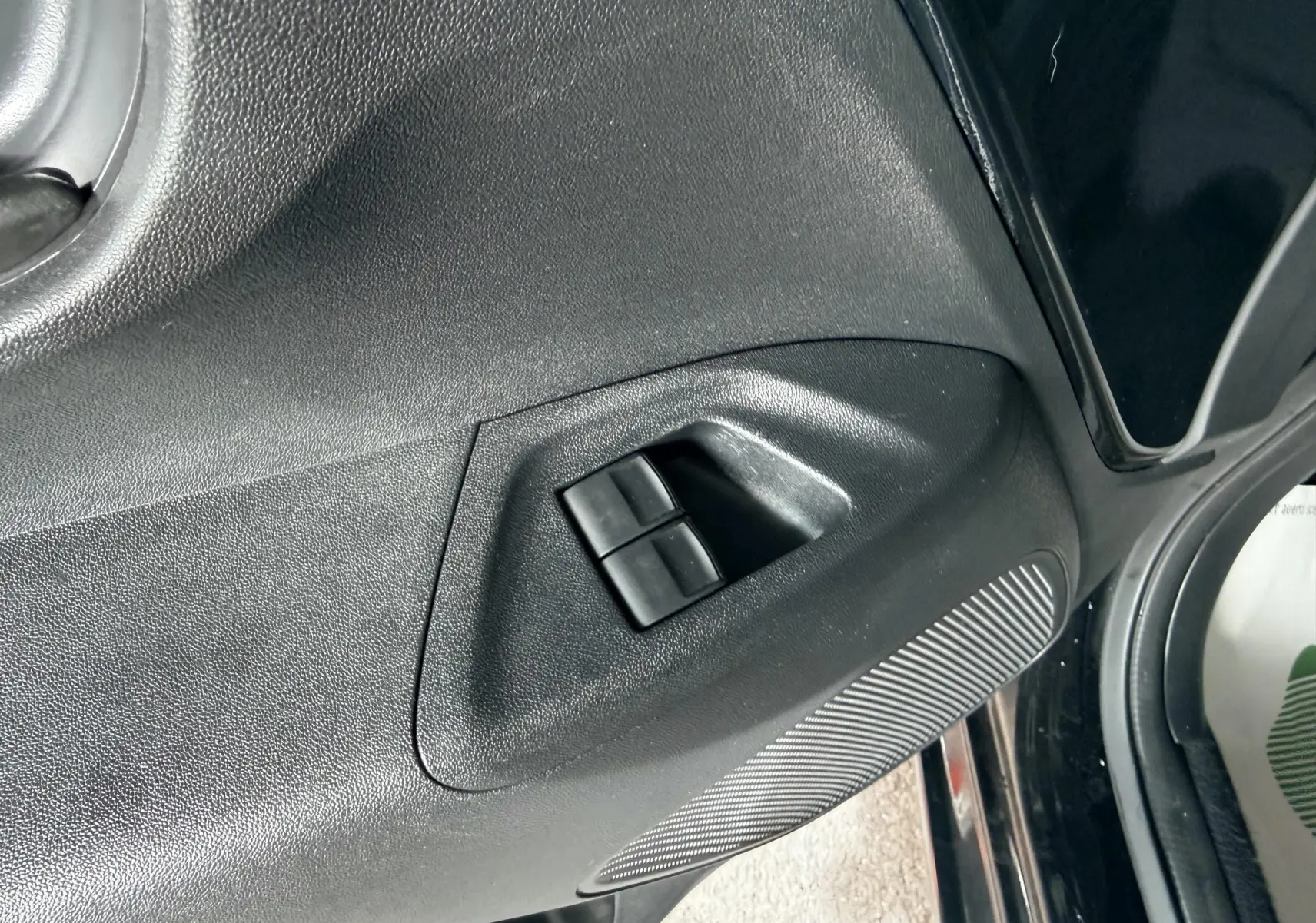 Détail des commandes de lève-vitres sur la porte avant gauche d'une Peugeot 108 noire de 2018.