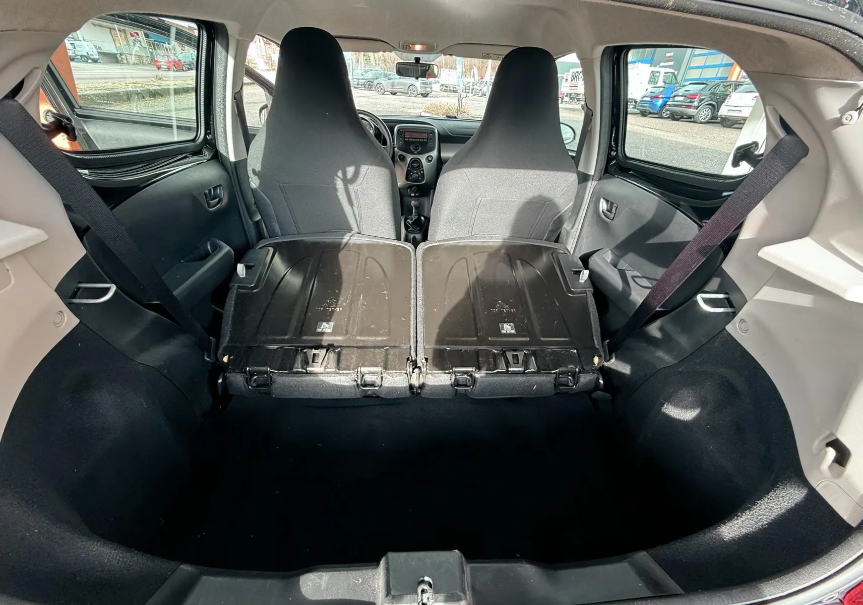Vue depuis le coffre du Peugeot 108 noir 2018 avec sièges arrière rabattus et intérieur gris noir en tissu.